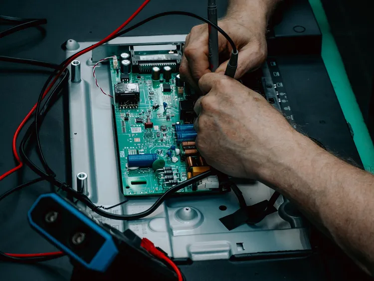 Técnico reparando a placa de uma televisão