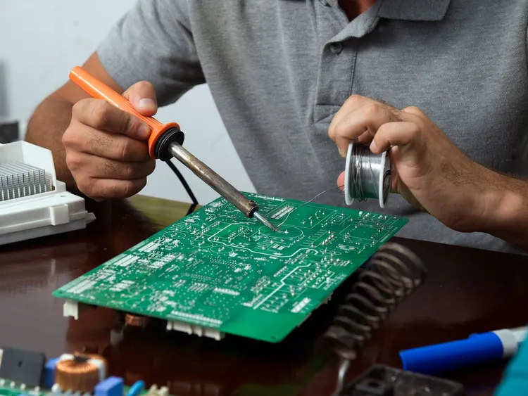 Técnico soldando componentes na placa eletrônica